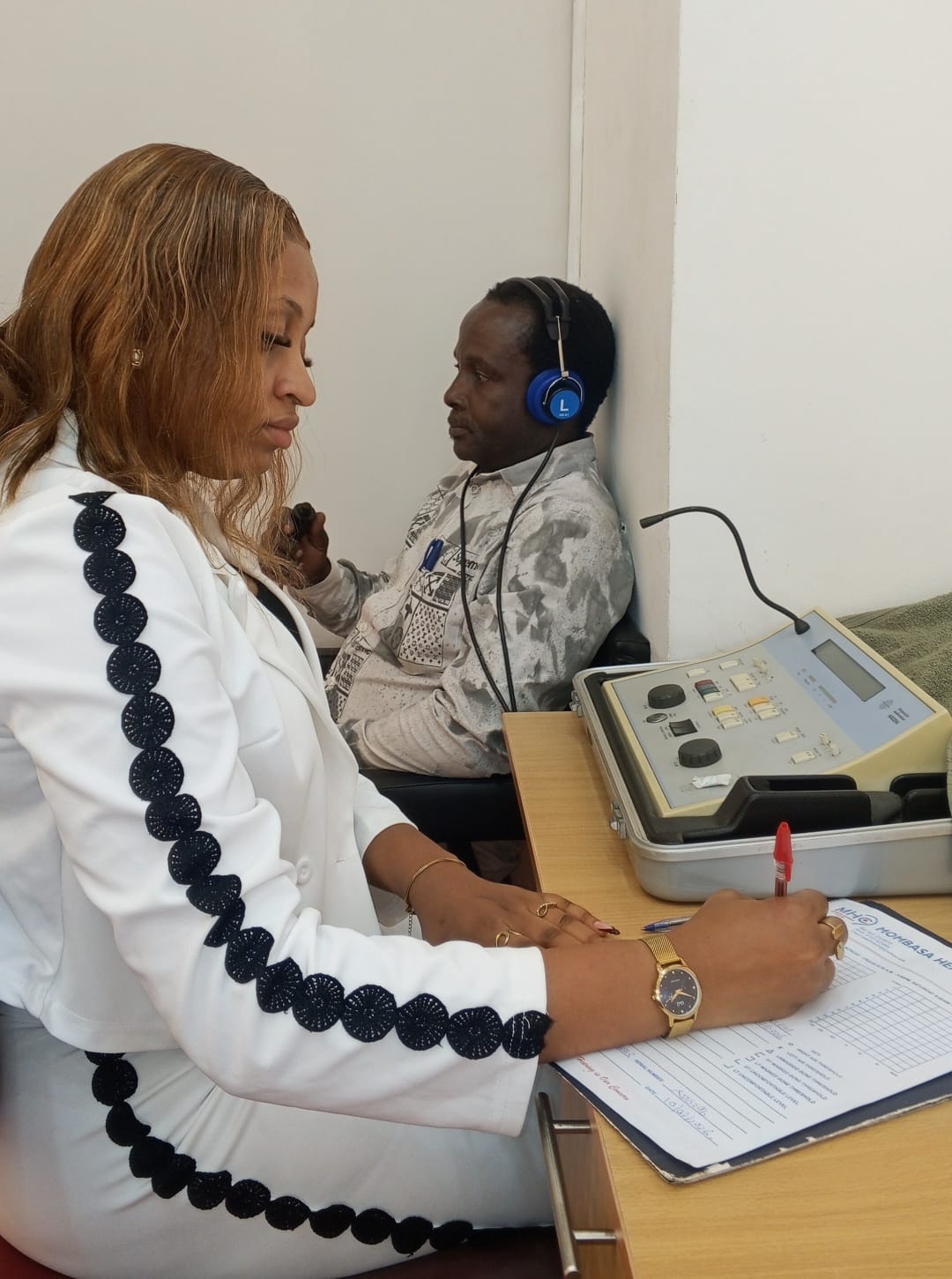 Madam Terry recording pure tone audiometry thresholds while a patient wears audiometric headphones